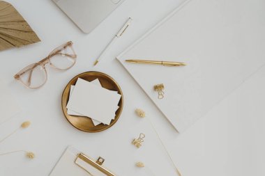 Kağıt kâğıt kâğıt kağıdında boş fotokopi alanı var. Gözlüklü ve altın renkli kırtasiyeli estetik ofis masası çalışma alanı. Asgari davet, markalaşma kartı şablonu