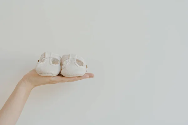 Dłoń Osoby Trzymać Słodkie Małe Sandały Dla Dzieci Buty Białym — Zdjęcie stockowe