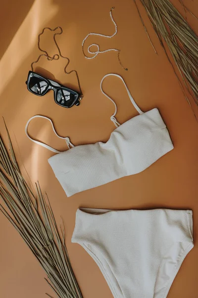 女性用水着 サングラス 太陽の影がぼやけているオレンジ色の背景に乾燥熱帯ヤシの葉 フラットレイアウト トップビューの最小限のファッションコラージュ 女性のファッションブログ ショッピングコンセプト — ストック写真