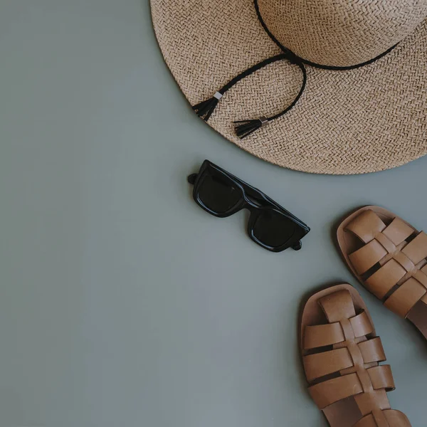 Flatlay of aesthetic women\'s fashion accessories. Stylish female sunglasses, straw hat, sandals on pastel blue copy space background. Top view, flat lay