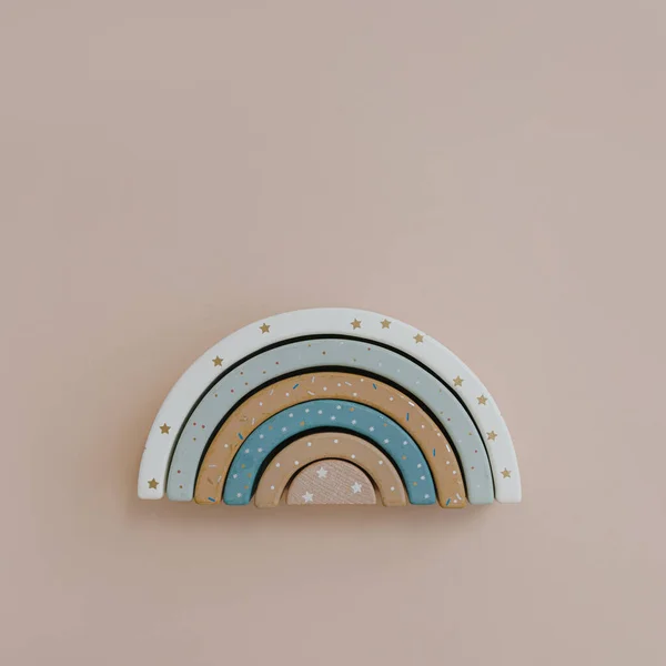 Colourful wooden rainbow stacking toy on neutral beige background. Aesthetic Scandinavian nordic eco stylish baby, children's toy. Flat lay, top view creativity concept