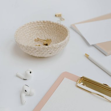 Clipboard, headphones, elegant women's accessories on white background with blank mockup copy space. Flat lay, top view minimalist home office desk workspace template