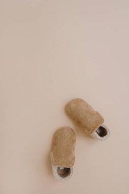 Sıcak kış çocukları için mini patik. Tarafsız bej arka planda bebek ayakkabıları. Moda İskandinav çocuk kıyafetleri. Düz yatış, üst görünüm.