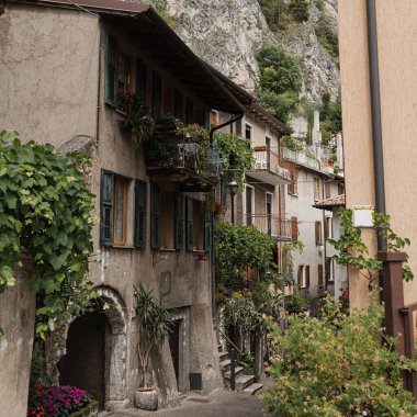 Kırsal İtalyan mimarisi. Geleneksel tarihi Avrupa kır binaları. Ahşap pencereleri, çiçekleri ve çiçek açan ağaçları var. Estetik yaz tatili seyahat kavramı