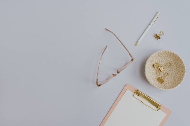 Bir sürü altın aksesuar ve ofis eşyası. Konforlu ofis çalışma alanı. Evde çalış. Pano, gözlük, klipsler, pastel masadaki kalem. Düz yatış, üst görünüm