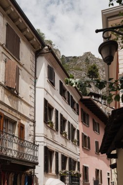 Eski tarihi İtalyan mimarisi. Geleneksel Avrupa köyü kır binaları. Çiçekler, ahşap pencereler, panjurlar ve güneş ışığı gölgeli pastel duvarlar. Estetik yaz tatili seyahat geçmişi