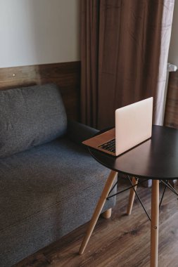 Evde çalış. Laptop bilgisayarı rahat kanepenin yanındaki sehpada. Modern minimal ev oturma odası iç tasarımı