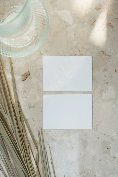 薄日の光の中で影のシルエットと大理石のテーブルの背景に空白のモックアップコピースペースと乾燥ヤシの葉と紙のシートカード — ストック写真