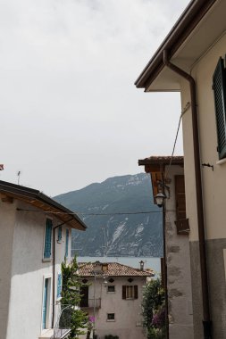 Kırsal İtalyan mimarisi. Geleneksel tarihi Avrupa kır binaları. Ahşap pencereleri, çiçekleri ve çiçek açan ağaçları var. Estetik yaz tatili seyahat kavramı