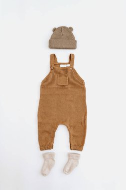 Set of knitted baby romper jumpsuit, jumper sweater, hat, sunglasses, socks on white background. Gender neutral baby clothes and accessories. Flat lay, top view