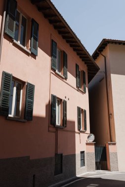 Eski İtalyan mimarisi. Geleneksel Avrupa eski kasaba binaları. Ahşap pencereler, panjurlar ve güneş ışığı gölgeli pastel duvarlar. Estetik yaz tatili
