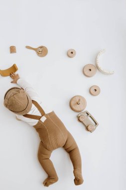 Kahverengi şapkalı şirin bir bebeğin şık ahşap oyuncaklarla oynaması. En az bebek modası çevrimiçi dükkan, online mağaza konsepti