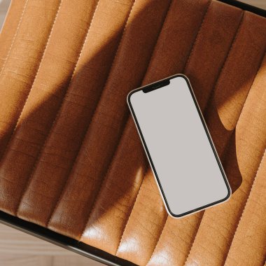 Estetik güneş ışığı gölgeli deri bankta fotokopi makineli cep telefonu
