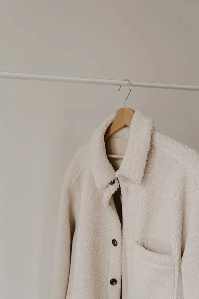 挂在白墙上方的衣架上的秋天外套 保暖的白色夹克有中性色彩衣服的审美衣橱 — 图库照片