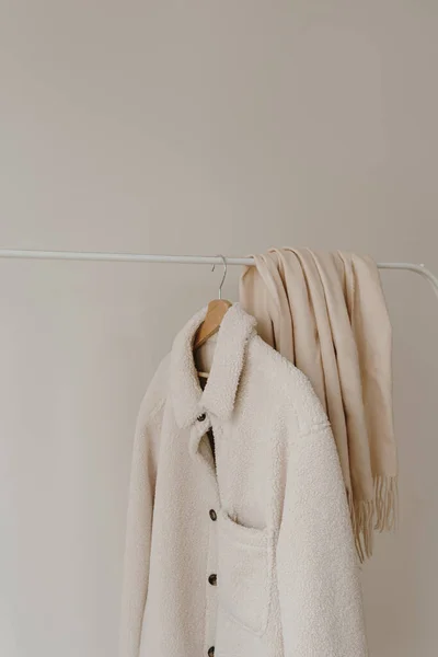 白色温暖的秋天羊毛夹克和裙子挂在白墙上方的衣架上 简约的时装衣橱 — 图库照片