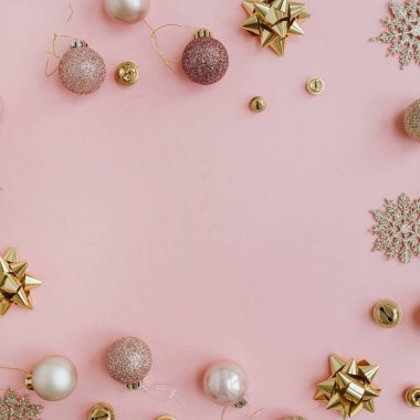 Zarif bir Noel kompozisyonu. Renkli Noel mücevherleri, toplar ve pembe arka plandaki yıldızlardan yapılmış boş fotokopi alanı ile çerçeveyi düzenle. Düz konum, üst görünüm tatil konsepti