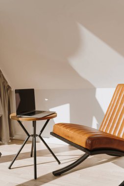 Minimalist modern ofis çalışma alanı iç tasarım konsepti. Deri koltuk, yan masada dizüstü bilgisayar. Duvarda estetik yumuşak güneş ışığı gölgeleri
