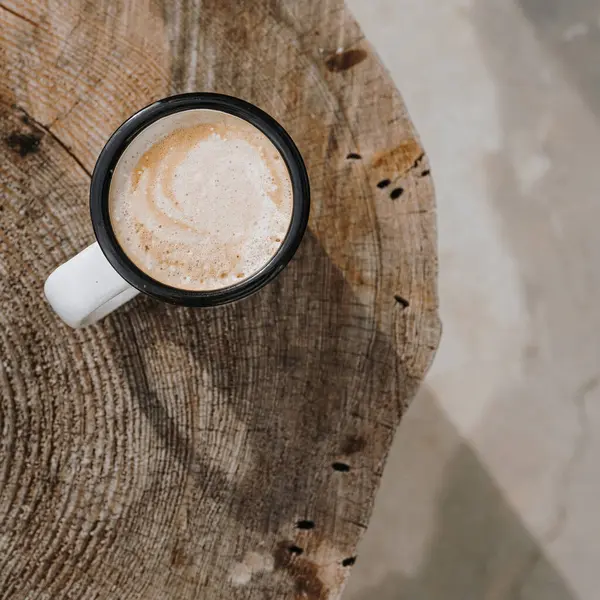 Coffee time! Flatlay mug with latte coffee on wood stump table. Minimalist morning breakfast background. Aesthetic flat lay, top view still life lifestyle concept