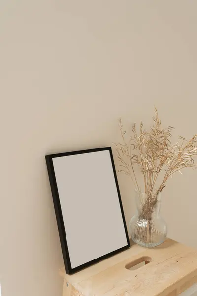 Photo frame with blank mockup copy space. Dried grass stems bouquet in glass vase on neutral beige background. Aesthetic minimal home interior design decoration