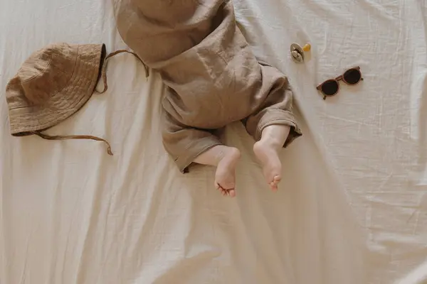 ベッドの上に横たわる新生児のトップビュー かわいいコージーリネンボディスーツ サングラス リトルベビーファッションコンセプト — ストック写真