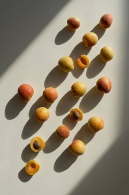 Estetik meyve arka planı. Şeftalili düz kompozisyon. Beyaz arka planda, güneş ışığı gölgeli olgun şeftaliler. Düz manzaralı. Taze organik meyve vejetaryeni.