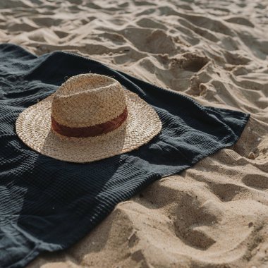 Hasır şapka, kumsaldaki plaj havlusu. Moda geçmişi çok az. Düz yatış, üst görünüm
