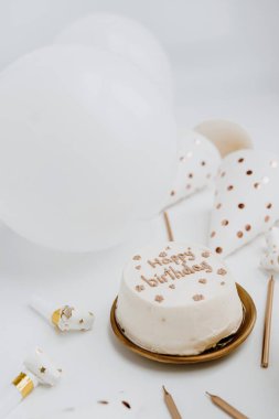 Doğum günü pastası, mumlar, balonlar, beyaz arka planda parti şapkaları. Beyaz ve altın renkleri