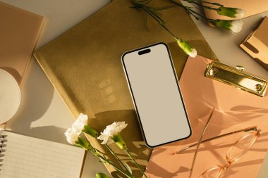 Beyaz perdeli akıllı telefon ve karanfil çiçekleri. Estetik güneş ışığı gölgeleri. Ofis masası çalışma alanı. Model kopyalama alanı ile en küçük iş markalaştırma şablonu