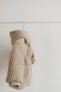 Bebeğin çocukları beyaz arka planda asılı duran kumlu pastel ceket giyerler. Yürüyen bebek modası
