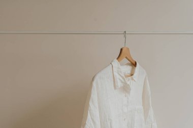 Beyaz buruşuk gömlek, beyaz duvarda asılı bluz. Estetik kadın kıyafetleri, kostüm konsepti.