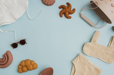 Şık İskandinav bebek plaj oyuncakları ve pastel mavi arka planda giysiler. Model için boş fotokopi alanı. Plajda oynamak için bebek eşyaları. Düz yatış, üst görünüm