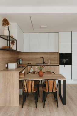 Modern parlak mutfak, beyaz mobilyalar ve ahşap yemek masası.