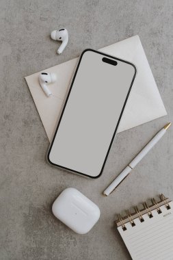 Flatlay cep telefonu, kablosuz kulaklık, kalem, beton masadaki defter. Estetik zarif blog, çevrimiçi alışveriş, çevrimiçi mağaza, boş kopya alanı olan sosyal medya marka şablonu