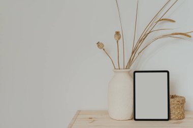 Boş fotokopi alanı olan tablet ekranı, kurutulmuş çimenli kil saksı, rattan tabut. Parlak estetik sosyal medya markası, çevrimiçi alışveriş şablonu