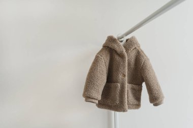 Beyaz duvarda asılı sevimli, sıcak çocuk kürkü ceketi. Bebek modası, alışveriş konsepti