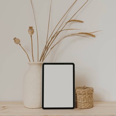 Boş fotokopi alanı olan tablet ekranı, kurutulmuş çimenli kil saksı, rattan tabut. Parlak estetik sosyal medya markası, çevrimiçi alışveriş şablonu