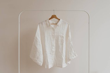 Beyaz buruşuk gömlek, beyaz duvarda asılı bluz. Estetik kadın kıyafetleri, kostüm konsepti.