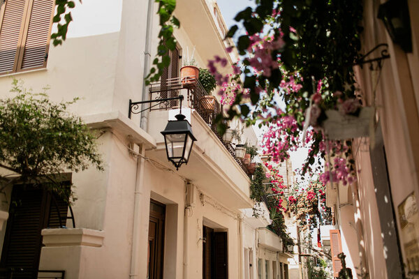 Вид на улицу со старыми средневековыми историческими зданиями и цветами в маленьком городке на Крите в Греции. Традиционная европейская, греческая архитектура. Летние путешествия