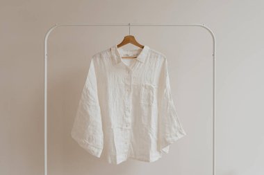 Beyaz buruşuk gömlek, beyaz duvarda asılı bluz. Estetik kadın kıyafetleri, kostüm konsepti.