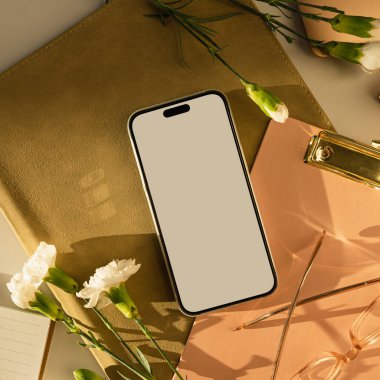 Beyaz perdeli akıllı telefon ve karanfil çiçekleri. Estetik güneş ışığı gölgeleri. Ofis masası çalışma alanı. Model kopyalama alanı ile en küçük iş markalaştırma şablonu