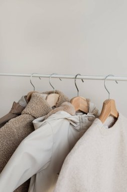 Beyaz duvarda asılı sevimli, sıcak çocuk kıyafetleri. Yağmurluk, kazak, ceket. Bebek moda alışveriş konsepti