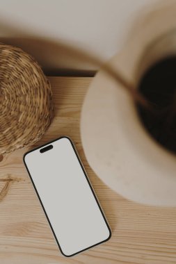 Düz bir cep telefonu, ahşap masa üzerinde rattan bir tabut. Estetik olarak boş boş cep telefonu ekranı ile kopyala. Düz yatış, üst görünüm