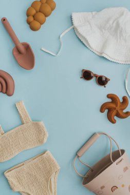 Şık İskandinav bebek plaj oyuncakları ve pastel mavi arka planda giysiler. Model için boş fotokopi alanı. Plajda oynamak için bebek eşyaları. Düz yatış, üst görünüm