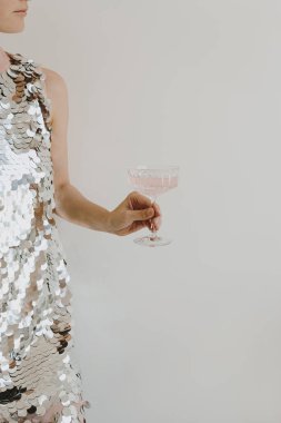 Parlak gece elbisesi giymiş, elinde pembe şampanya kadehi tutan güzel bir kadın. Noel, yeni yıl tatili parti kutlaması. Şerefe kavramı