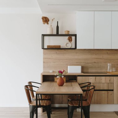 Modern parlak mutfak, beyaz mobilyalar ve ahşap yemek masası.