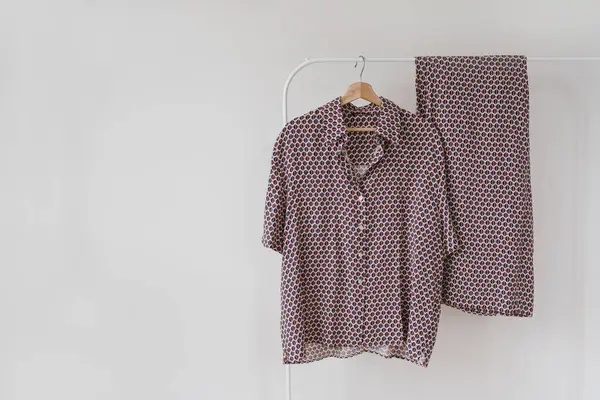 Beyaz arkaplanda asılı mor pijamalar.