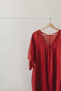 Beyaz duvarın üzerinde kırmızı elbise askısı. Estetik moda kıyafetleri