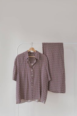 Beyaz arka planda asılı mor pijamalar. Gömlek ve pantolon askıda.