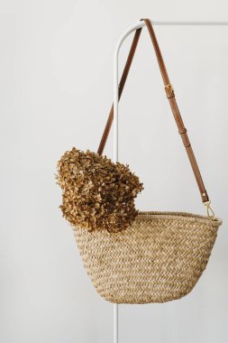 Zarif moda aksesuarı. Askıda kurutulmuş ortanca çiçekli saman el çantası. Moda günlüğü, kopyalama alanı olan sosyal medya şablonu