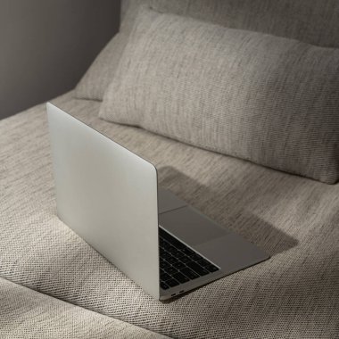 Dizüstü bilgisayar rahat kanepede, güneş ışığı gölgeli. Ev konseptinde çalış